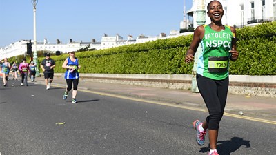 A member of Team NSPCC running and smiling during an event.