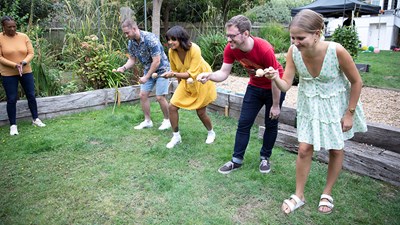 Some fundraisers laughing and smiling while taking part in an egg and spoon race.