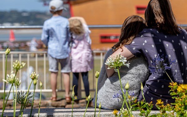 A female carer and a young girl hugging each other at the beach.