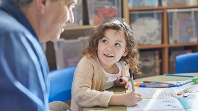 A young girl drawing in a colouring book.