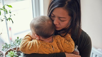 Mother suffering with perinatal mental health holds her baby close to her chest