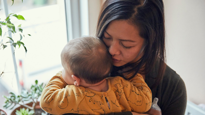 Mother with perinatal mental health issues cradling her baby