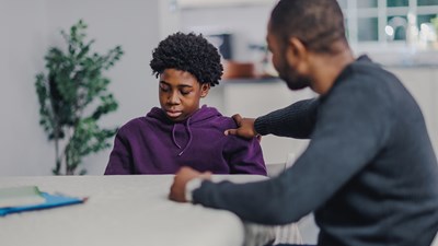 A teenager being consoled by their parent/carer.