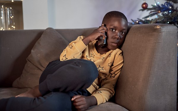 A child sat beside a Christmas tree while making a phone call.