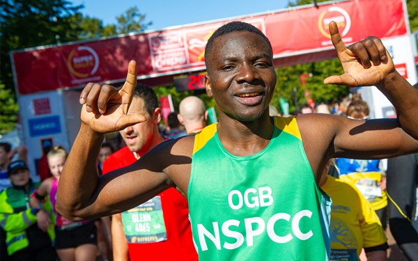 A man raising his hands to celebrate reaching the finish line of a half marathon