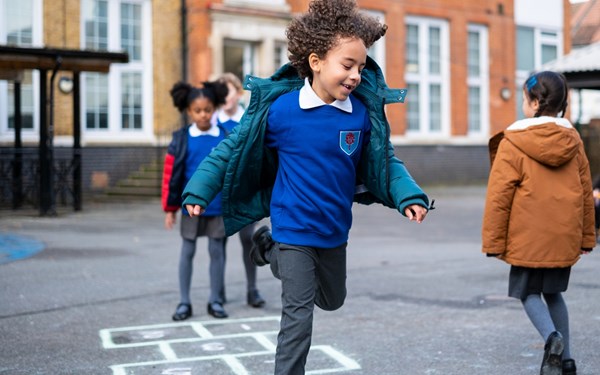 A young boy smiling while playing in a school playground.